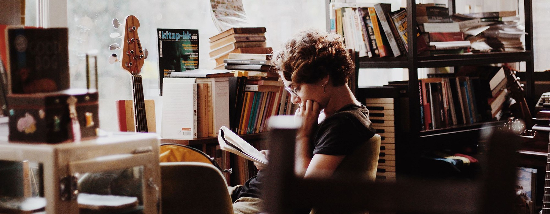 girl reading near bookshelf